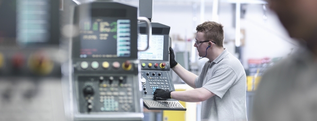 Mand arbejder ved en CNC-maskine i en industrihal
